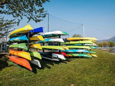Kayak colorati impilati su un prato vicino al lago.