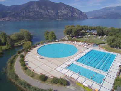 Piscina all'aperto vicino a un lago con montagne sullo sfondo.