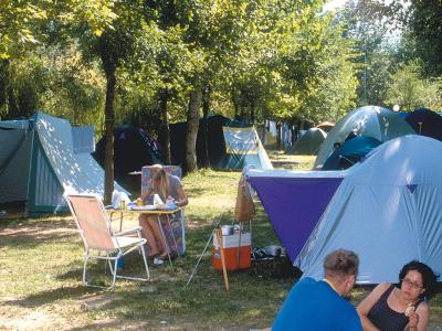 Persone che campeggiano in una foresta con tende e attrezzature da campeggio.
