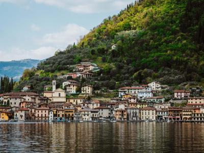 Paesino pittoresco tra lago e collina verde.