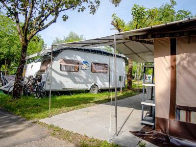Campeggio con roulotte, biciclette e veranda in un ambiente verde.