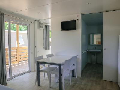 Interno moderno con tavolo, sedie, TV e accesso al balcone.