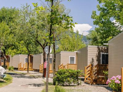 Bungalows in a campsite surrounded by trees and mountains.