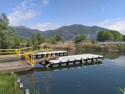 Dock with yellow railing on lake, mountains in the background.