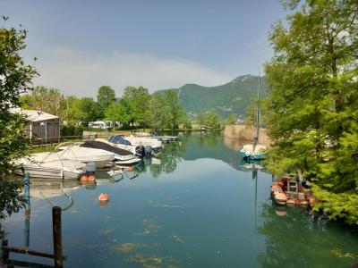 Boats moored in a canal surrounded by trees and mountains.