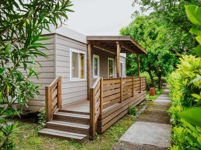 Modern wooden house with a porch surrounded by greenery.