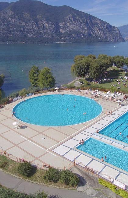 Outdoor pool by a lake with mountains in the background.