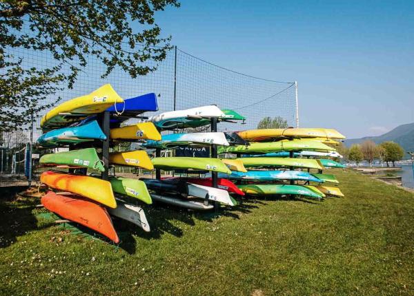 Kayak colorati impilati su un prato vicino al lago.