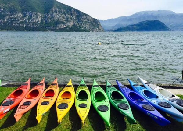 Colorful kayaks lined up by the lake with mountains in the background.