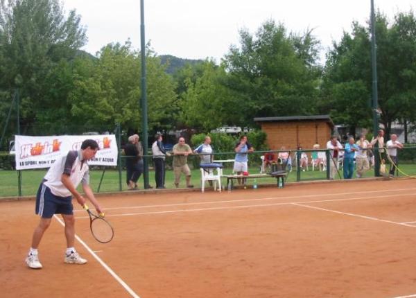 Giocatore di tennis pronto a servire su un campo in terra battuta.