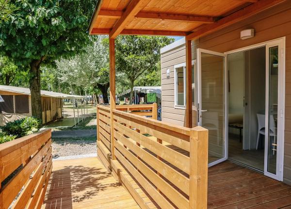 Veranda di legno di una casa mobile in un campeggio ombreggiato.