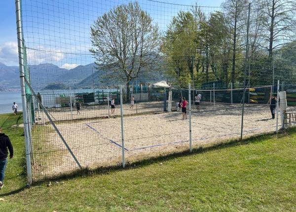 Beach volleyball game by the lake with mountain view.