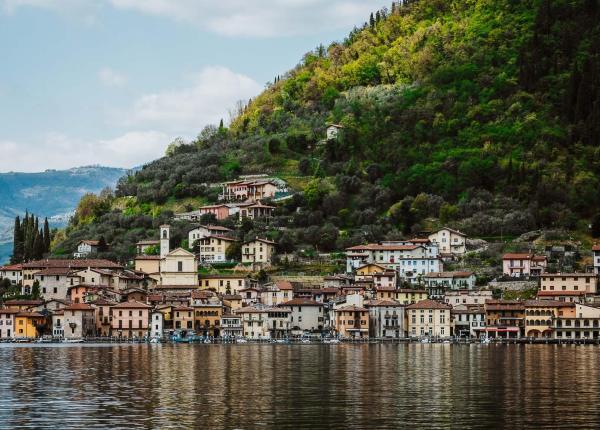 Paesino pittoresco tra lago e collina verde.