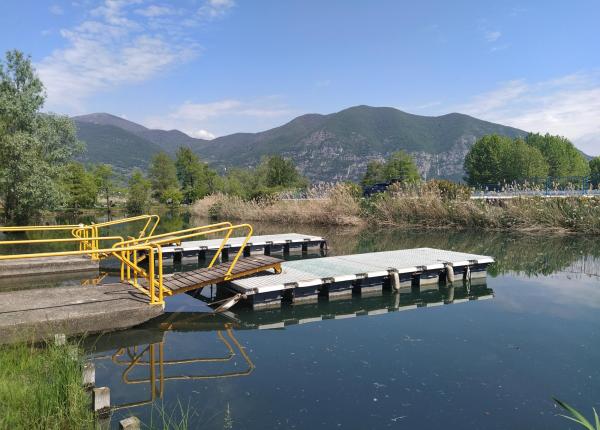 Dock with yellow railing on lake, mountains in the background.