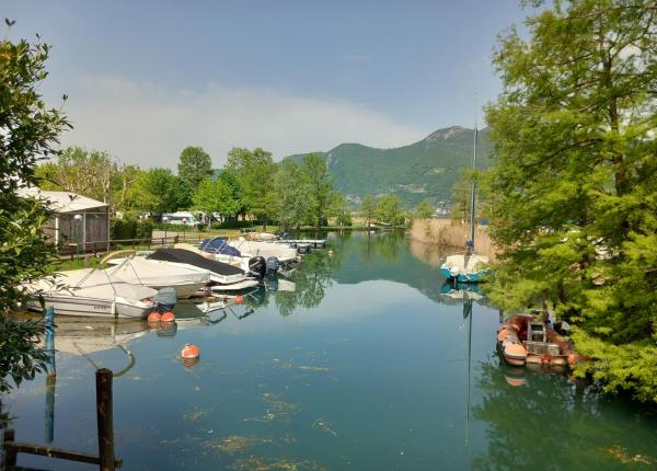 Boats moored in a canal surrounded by trees and mountains.